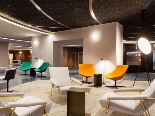 - une salle d'attente avec des chaises et des tables colorées dans l'établissement Pullman Paris Montparnasse, à Paris