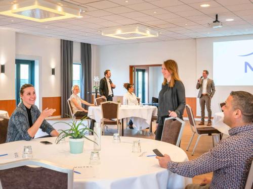 Un groupe de personnes assises autour d'une table dans une pièce dans l'établissement Novotel Marne-la-Vallée Noisy-le-Grand, à Noisy-le-Grand