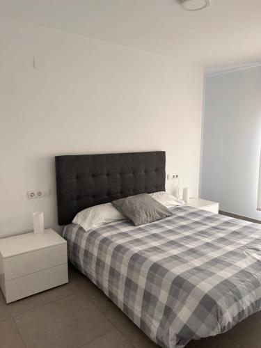 a bedroom with a large bed with a checkered blanket at Apartamentos CorteInglés Castellón by Tucasanlaplaya in Castellón de la Plana