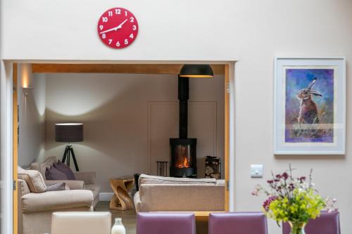 a living room with a fireplace and a clock on the wall at Brockram Barn in Kirkby Stephen