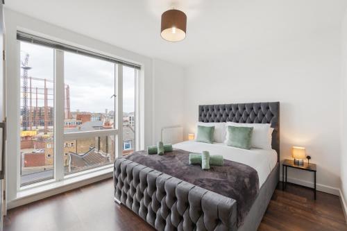 um quarto com uma cama grande e uma janela grande em Modern Shoreditch flat next to station with lift and views em Londres