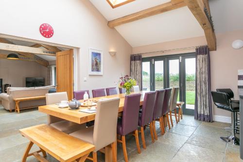 a dining room and living room with a wooden table and chairs at Brockram Barn in Kirkby Stephen