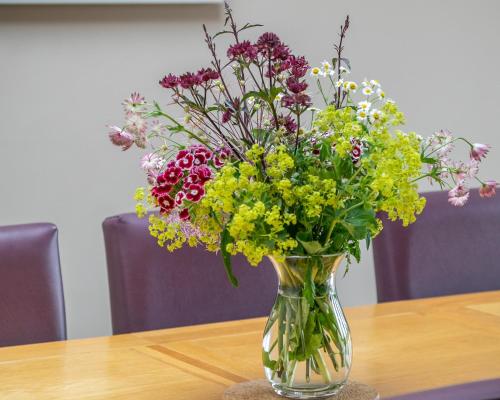a glass vase filled with flowers on a table at Brockram Barn in Kirkby Stephen