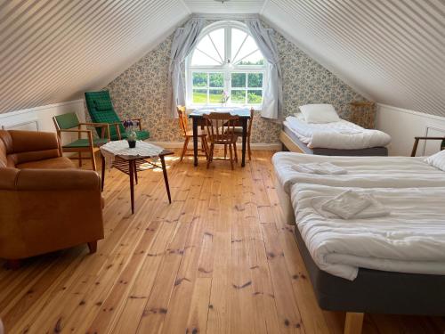 um quarto no sótão com 2 camas, uma mesa e cadeiras em Spjutsbygds Gårds Bed and Breakfast em Rödeby