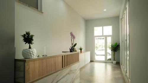 um corredor com paredes brancas e uma escada com plantas em Gent's Inn em Durrës