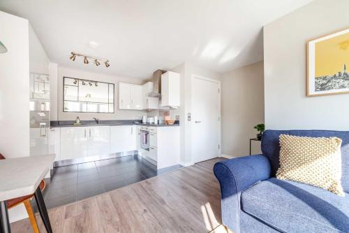 a living room with a blue couch and a kitchen at Cosy East London Retreat in London