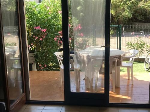 Une porte ouverte s'ouvre sur une terrasse avec une table et des chaises. dans l'établissement Grand Studio rez de jardin avec parking à 5 min à pieds de la mer et commerces, à Calvi