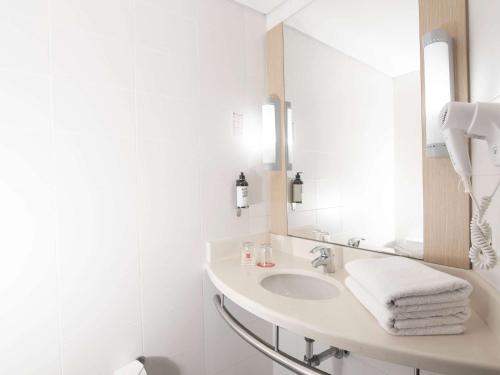 een witte badkamer met een wastafel en een spiegel bij ibis Medellin in Medellín