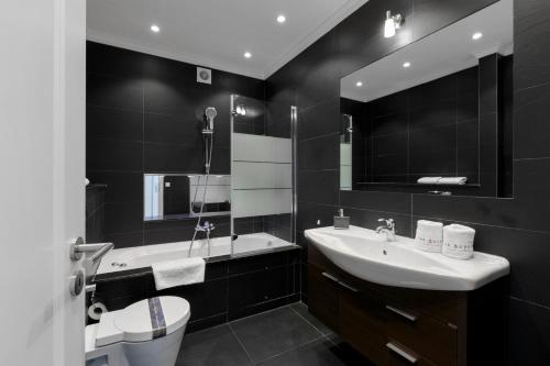 W łazience znajduje się umywalka, toaleta i lustro. w obiekcie The Queen Luxury Apartments - Villa Fiorita w Luksemburgu