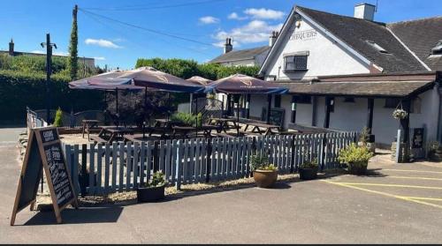 a restaurant with tables with umbrellas and a fence at Chequers Country Inn in Lutterworth