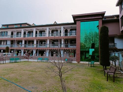 een groot gebouw met een binnenplaats met banken ervoor bij Hotel Kashmir Hilltown, Srinagar in Moniawār