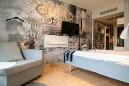 Schlafzimmer mit einem Bett, einem TV und einem Stuhl in der Unterkunft Scandic Malmen in Stockholm