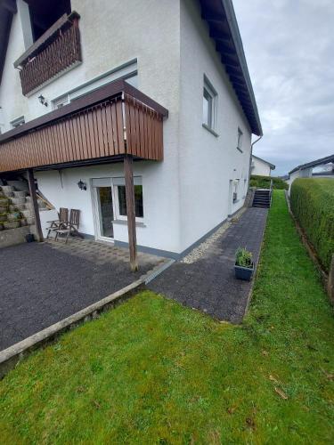 ein Haus mit einer Terrasse und einem Rasenhof in der Unterkunft Widmanns Ferienquartier in Wiehl