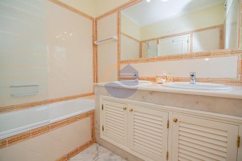 a bathroom with a sink and a tub and a mirror at Villa Luxury Suites, Heated Outdoor Pool in Portimão