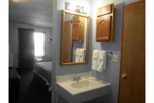 a bathroom with a sink and a mirror and a bed at Columbus Motel in Columbus Junction