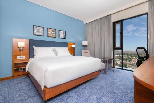 um quarto com uma cama grande e uma janela grande em Hilton Garden Inn Windhoek em Windhoek