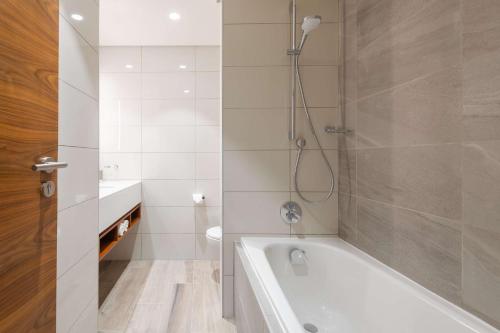 La salle de bains est pourvue d'une baignoire, de toilettes et d'une douche. dans l'établissement Hilton Garden Inn Windhoek, à Windhoek