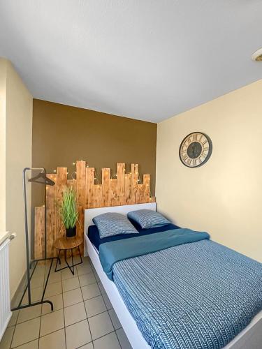 une chambre avec un lit et une horloge au mur dans l'établissement Échappée Belle à Épinal, à Épinal