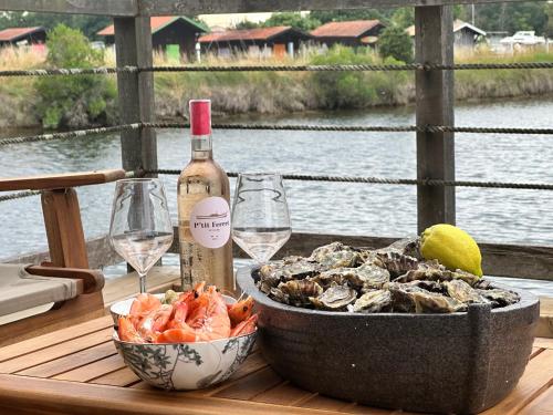 - une table avec un bol de crevettes et une bouteille de vin dans l'établissement Un air de paradis, à Gujan-Mestras