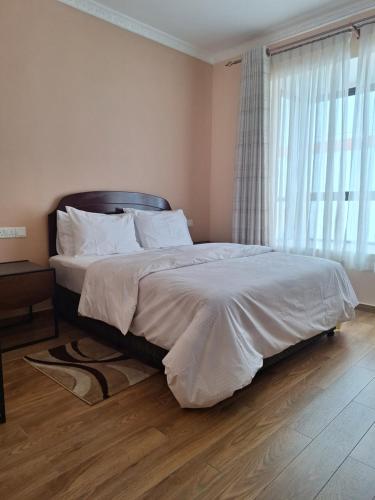 a bedroom with a bed with white sheets and a window at Sabra Palmvillage mikocheni in Dar es Salaam