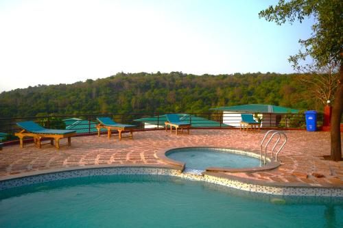 a swimming pool with tables and benches around it at Cashew leaf resort in Arambol