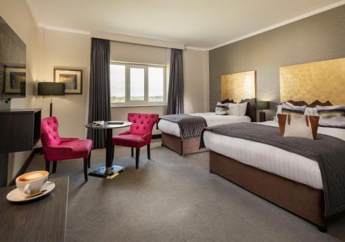 Cette chambre d'hôtel comprend deux lits, une table et des chaises. dans l'établissement Talbot Hotel Carlow, à Carlow