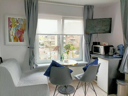 ein Wohnzimmer mit einem Tisch, Stühlen und einem Fenster in der Unterkunft Pension Schier in Zandvoort