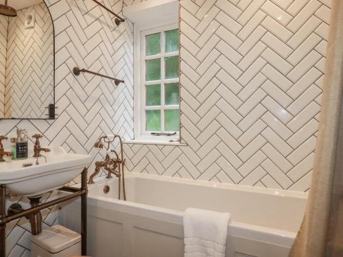 a bathroom with a white tub and a sink at Waterside Cottage in Truro