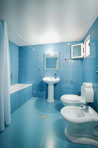 a blue bathroom with two toilets and a sink at Vila Limos in Ksamil