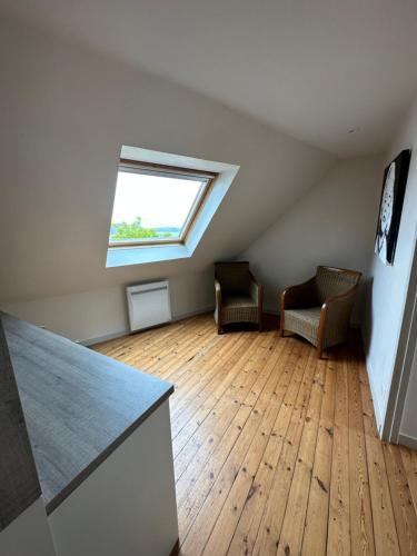 um quarto no sótão com 2 cadeiras e uma janela em Presqu’île Crozon-Morgat em Crozon