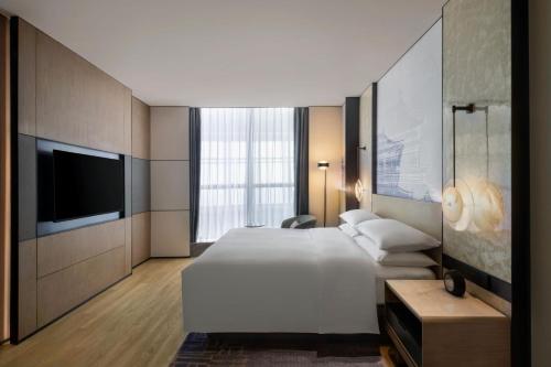a hotel room with a large bed and a flat screen tv at Wuhan Marriott Hotel Wuchang in Wuhan