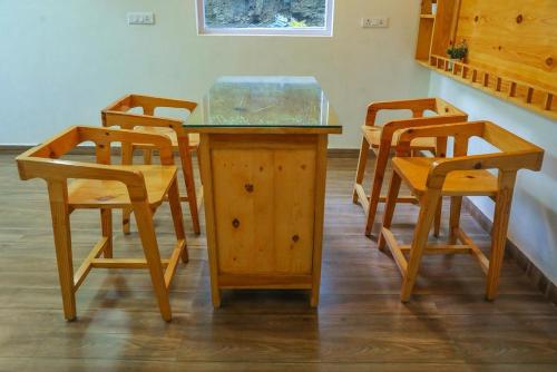 una mesa de madera y sillas con encimera de cristal en Aaryam villa en Mukteswar
