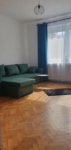 a living room with a green couch and a wooden floor at Mieszkanie w domu jednorodzinnym in Człuchów