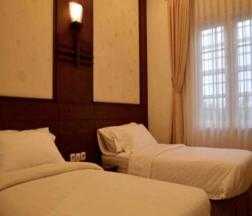 a hotel room with two beds and a window at Cove Ottenville Boutique Hotel in Bandung