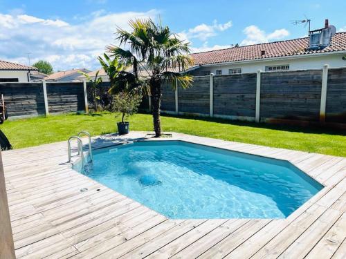 - une piscine dans une cour avec une terrasse en bois dans l'établissement Villa jardin clos - piscine & jacuzzi privatif - animaux acceptés, à Gujan-Mestras