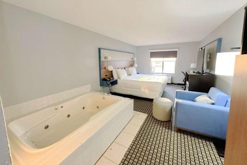 a large bathroom with a large tub and a bed at AmericInn by Wyndham Reedsburg in Reedsburg