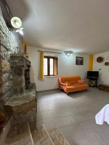 sala de estar con sofá naranja y chimenea de piedra en Appartamento La Petrosa, en Nova Siri