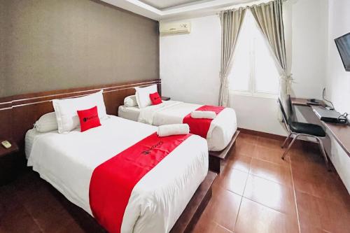 a hotel room with two beds and a desk at RedDoorz @ Best Hotel Jalan Dr. Sutomo Siantar in Pematangsiantar