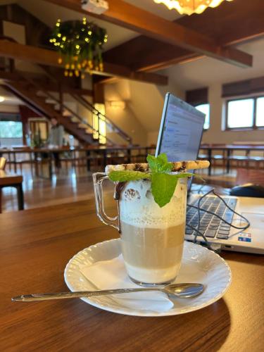 een kopje koffie op een bord op een tafel bij Hotel Vesta Centrum Konferencyjno Wypoczynkowe in Jeleśnia