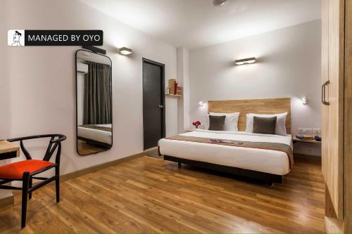 a bedroom with a bed and a chair and a mirror at Townhouse Greater Kailash Near Kailash Colony Metro Station in New Delhi