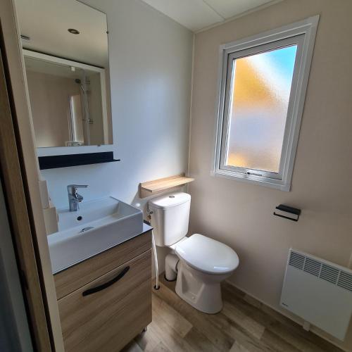 une salle de bain avec toilettes, lavabo et fenêtre dans l'établissement Joli Bungalow Cap Ferret Camping les Viviers, à Lège-Cap-Ferret
