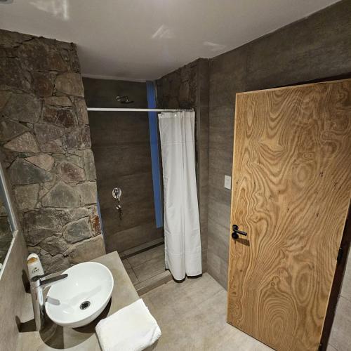 a bathroom with a sink and a shower with a door at Cabañas Bodega Kindgard in Purmamarca