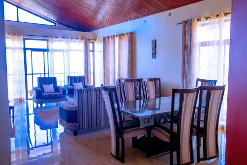 een eetkamer met een tafel, stoelen en ramen bij Kigali Village Suites in Kigali