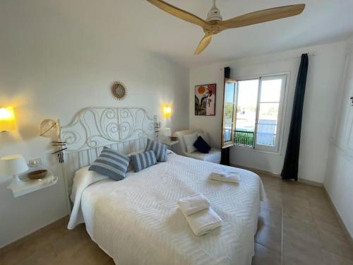 1 dormitorio con 1 cama blanca y 2 toallas en ALGAIARENS Apto con piscina y junto a la playa, en Cala en Blanes