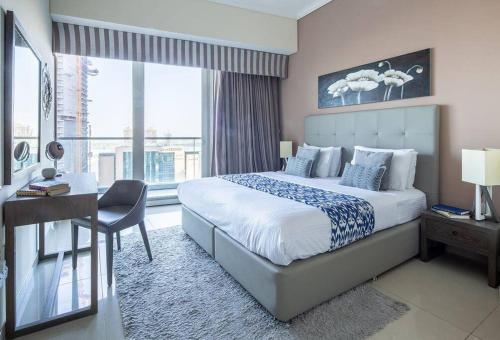a bedroom with a bed and a desk and a window at Frank Porter - Ocean Heights in Dubai