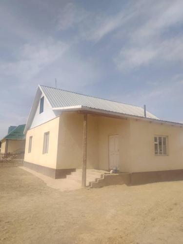 una pequeña casa blanca con una puerta y un patio de tierra en Ak-Tal guesthouse, en Akkyya