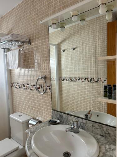 a bathroom with a sink and a toilet and a mirror at Apartaments Superiors MTB Only Couples in Lloret de Mar