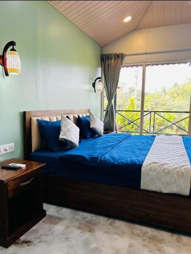 a bedroom with a blue bed and a window at 4D's Coast,Vagator in Vagator