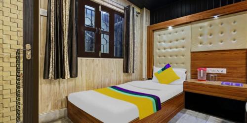 a small bedroom with a bed with a yellow pillow at Hotel Flatties Mall Road Lake View Nainital - Excellent Service Recommended in Nainital