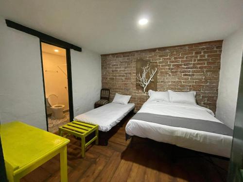 a bedroom with two beds and a brick wall at BOSQUE DE NIEBLA in Pijao